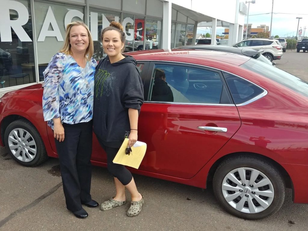 Tiffany Weideman Standing with a Happy Customer and her New Vehicle