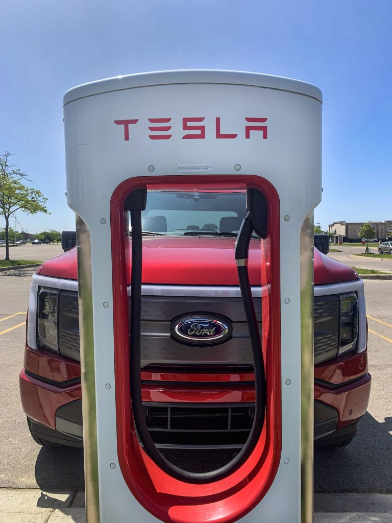 A Ford F-150 Lightning at a Tesla charging station