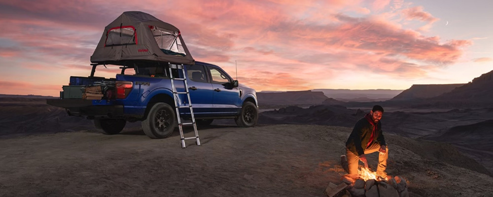 Person camping at sunset with a roof tent on their Ford F-150