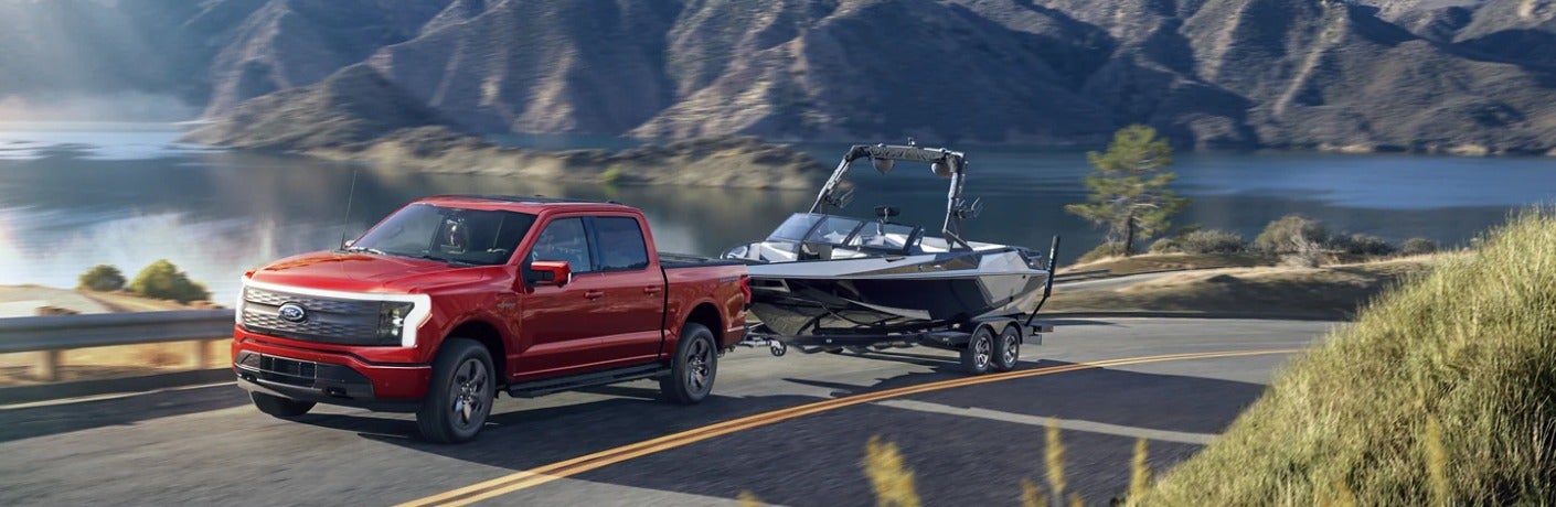 2023 Ford F-150 Lightning in red towing a boat